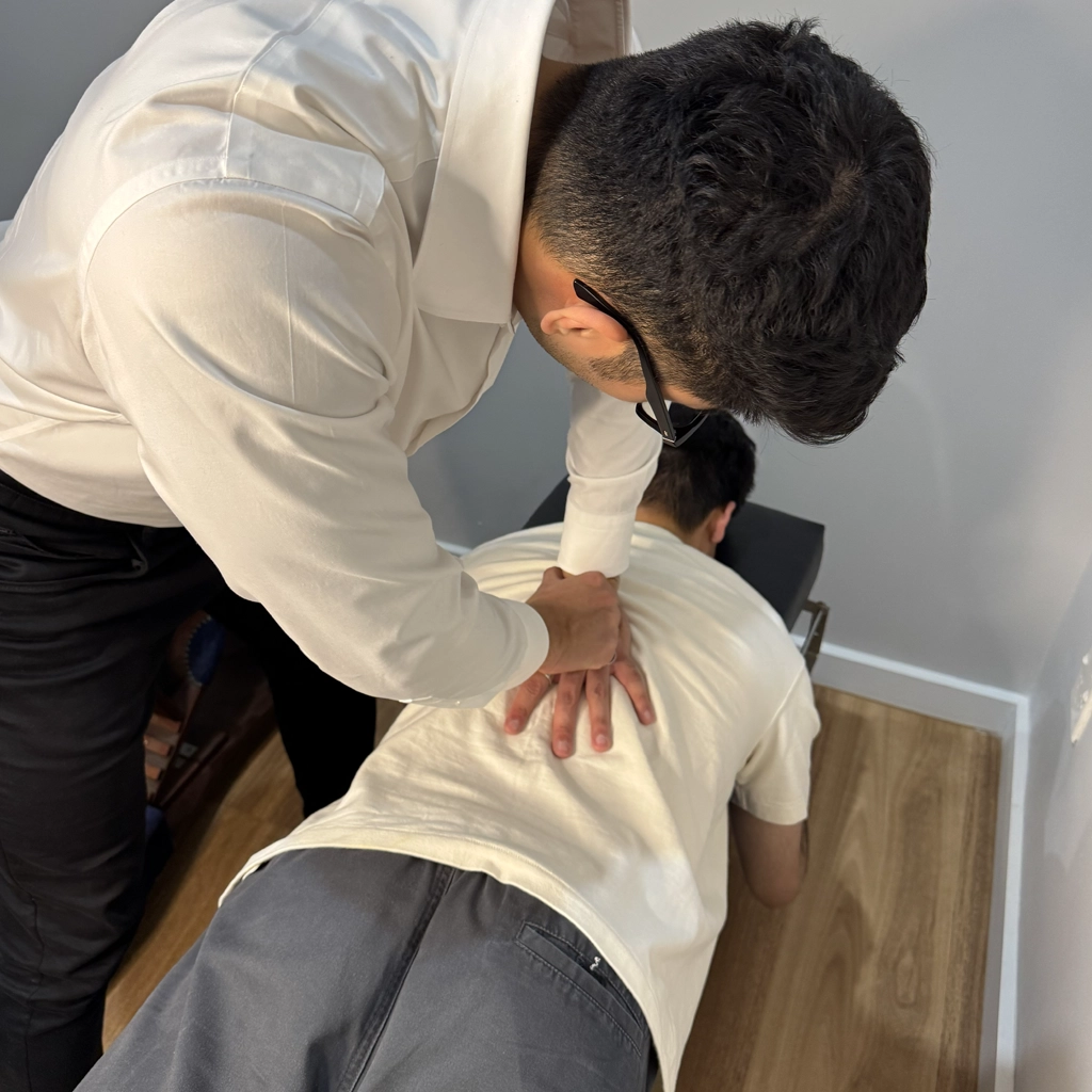 Ringwood chiropractor applying a manual thoracic adjustment on a male patient on the adjustment table.